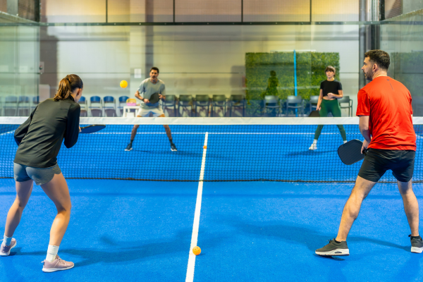 Blue pickle ball court with four adult players.